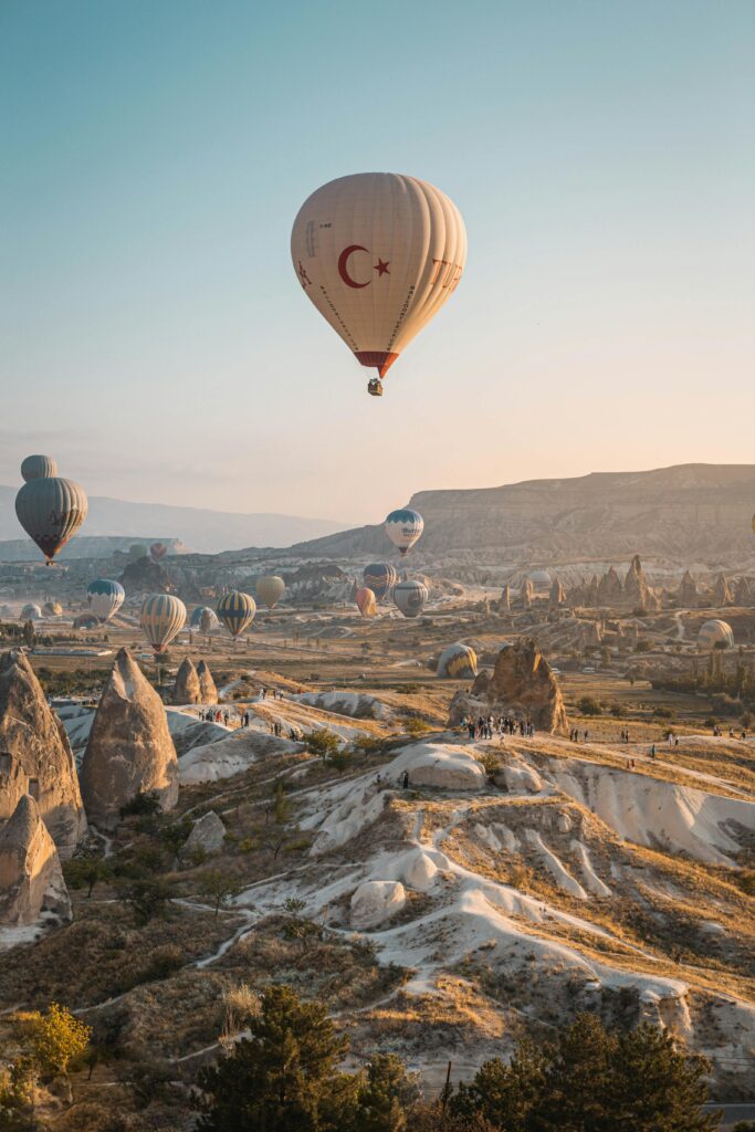 pexels-photo-7566847-7566847 Hot air balloons float above Cappadocia's unique landscape at sunrise, offering a breathtaking aerial view.